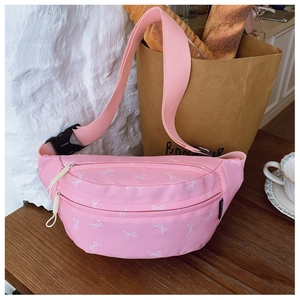 Detail of pink kids waist bag with white bow pattern on a wooden table setting