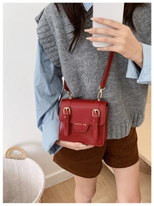 Detail of red leather messenger bag with gold buckles and adjustable shoulder strap