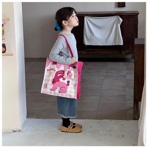 Detail of pink plaid canvas tote bag with rabbit print and charm on a child model