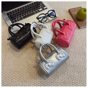 Detailed view of mini cylinder handbags in black, white, pink, and silver with bows