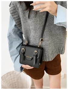 Close-up of black retro messenger bag for kids with gold lettering and metallic buckles