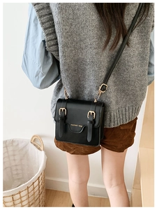 Detail view of the black retro messenger bag with golden buckles and fashion bag text