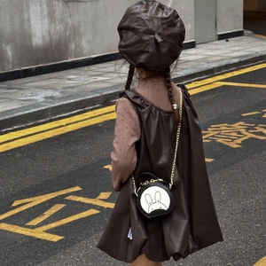 Rear view of child in brown leather dress with cute rabbit round chain crossbody bag