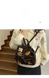 Detail of dark brown leather school backpack with cartoon patches on a wooden staircase