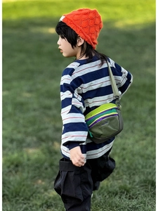 Close-up of colorful nylon kid's crossbody bag with adjustable strap on grass