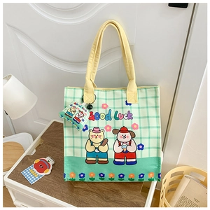 Detail of green checkered canvas tote bag with cute cartoon pets and mini charm