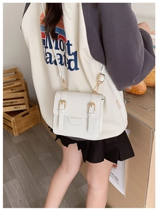 White faux leather crossbody bag with dual decorative buckles and adjustable strap