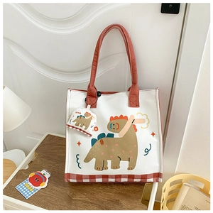 Detail of canvas tote bag with cartoon dinosaur print, red handles and matching small coin pouch