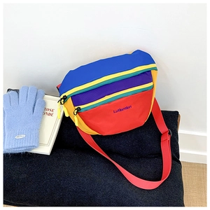 Detail of colorful nylon kids crossbody bag with multi-compartment zippers and red strap