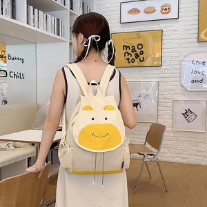 Sac à dos vache mignon en toile crème et jaune, porté par un mannequin dans un café