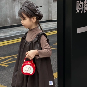 Kid carrying a red round shoulder bag with rabbit design on a city street scene