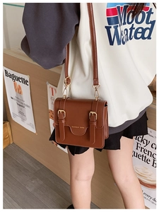 Close-up of retro brown PU leather messenger bag with metal hooks and adjustable strap