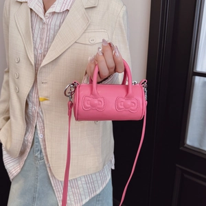 Pink mini barrel bag with embossed bows, twin handles, and crossbody strap for girls