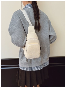 Detail der cremeweißen Cord-Brusttasche mit verstellbarem Gurt und Reißverschlussfächern