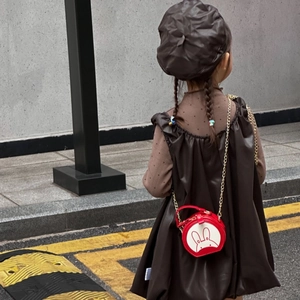 Rear view of mini red rabbit round purse with gold chain on dark brown leather dress