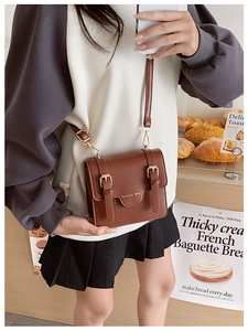 Detail of vintage brown children's messenger bag with metal buckles and fashion text