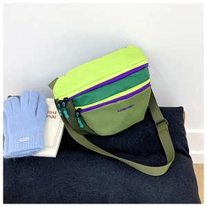 Detail of colorful kids crossbody bag featuring tricolor green panels and purple zipper accents
