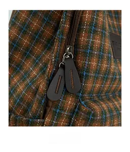 Detail of smooth double metal zippers and leather pullers on a plaid kids backpack
