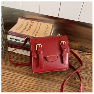 Detail of red vintage faux leather kids messenger bag with gold fashion bag logo