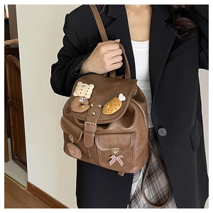 Detailed view of brown leather backpack with cute plush food charms and bow decoration