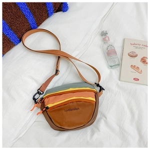 Detail of multi-color block crossbody bag with adjustable strap on white linen background