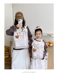Close-up of quilted floral backpacks with bear charm and Merci embroidery for kids