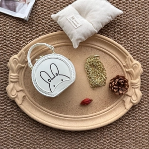Detail view of the mini round white leather bunny bag with a gold chain strap