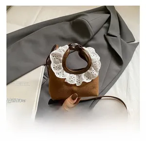 Détail du mini sac bandoulière marron avec broderie en dentelle sur l'anse ronde