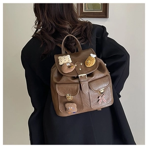 Close-up of dark brown vintage school backpack with cute plush charms on black blazer