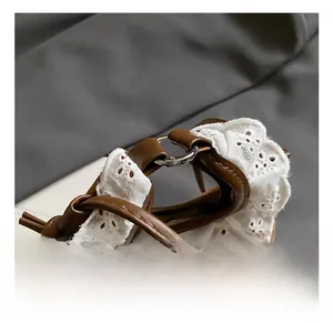 Détail du sac bandoulière marron avec broderie en dentelle blanche et anses en cuir