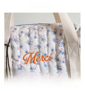 Detail of floral quilted backpack with orange Merci embroidery and brown bear charm