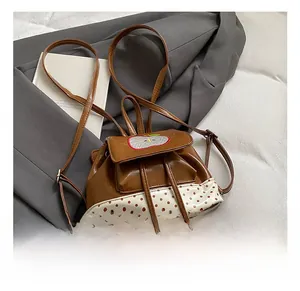 Detail view of mini apple backpack with polka dot print and glossy brown PU leather