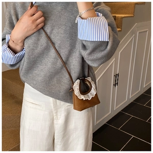 Détail d'un mini sac bandoulière en daim marron avec bordure en dentelle blanche délicate