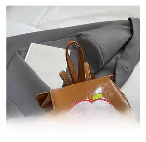 Detailed view of comfortable handle and apple embroidery on vintage leather mini backpack