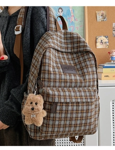 Detail of classic plaid children's backpack with plush dog charm and leather logo patch