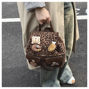 Detailed view of leopard print backpack with cartoon food patches and leather trim