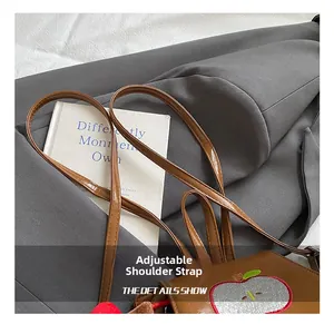 Detail of adjustable shoulder strap and apple embroidery on brown kids backpack