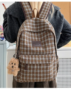 Rear view of child wearing plaid backpack with brown dog plush toy accessory