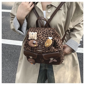 Detail of leopard print kids backpack with plush pins and brown leather accents