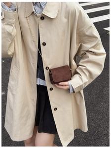 Detailansicht braune Wildleder Mini-Umhängetasche mit Goldkette auf einem Trenchcoat