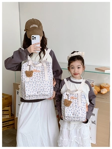 Matching parent-child quilted floral backpacks with Merci embroidery and bear charms