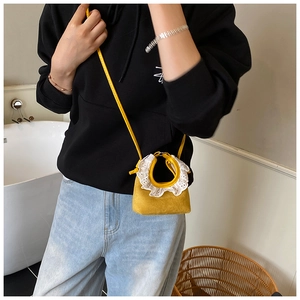 Detail of yellow suede mini crossbody bag featuring white lace trim and slim strap