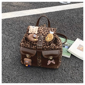 Detail of leopard print backpack with plush patches and bow on street asphalt background