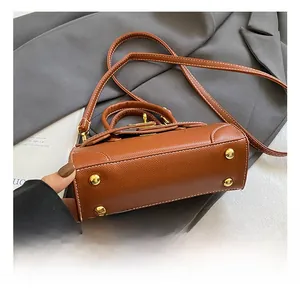 Detail view of brown pebbled leather bag base with four protective gold metal studs