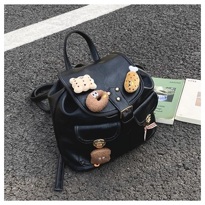 Outdoor view of children's black faux leather backpack with cute plush food charms