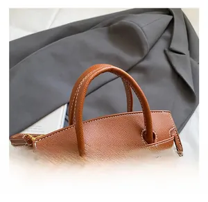 Detail of brown litchi grain leather handbag with white stitching and gold lock