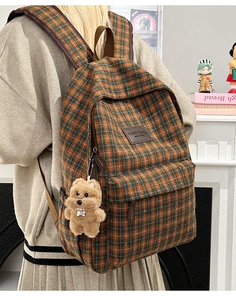 Detail of plaid kids backpack with leather label and cute brown plush bear charm