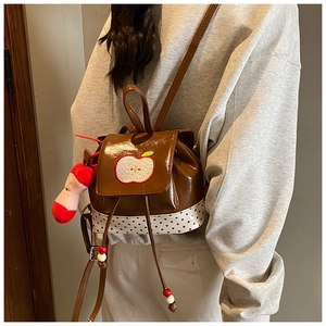 Detail of cute apple embroidery and red polka dot fabric on mini glossy patent backpack