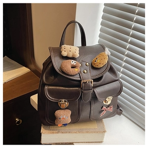 Detail of dark brown faux leather backpack with plush charms and gold twist locks