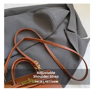 Detail of brown lychee leather handbag with adjustable strap and gold metal lock
